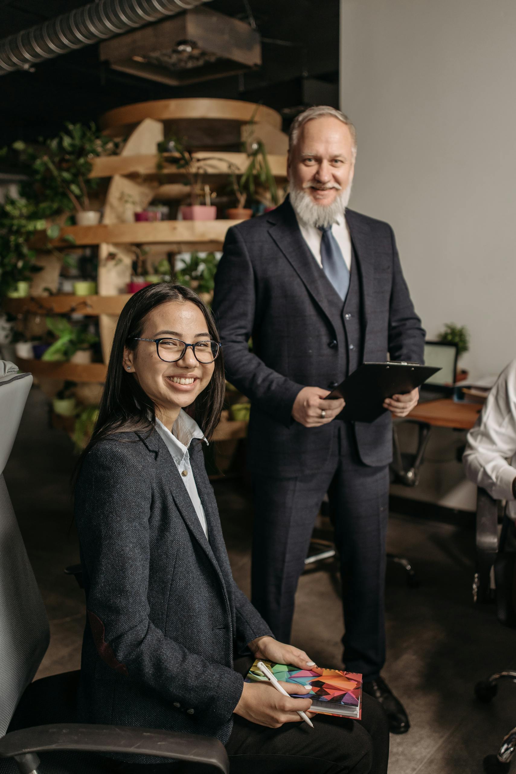 Smiling business professionals in a modern office setting during a meeting.